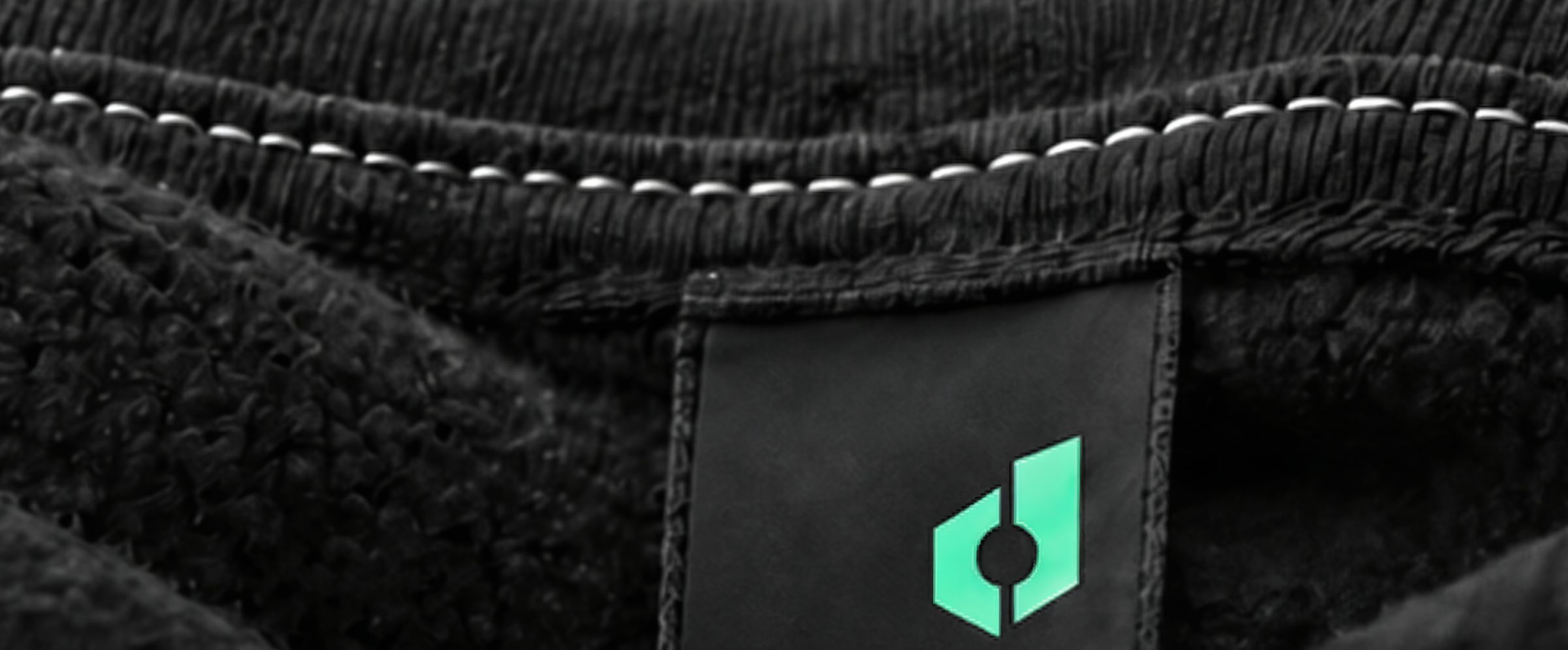 Close up: the woven dropPLM label inside the collar of a black fleece sweatshirt